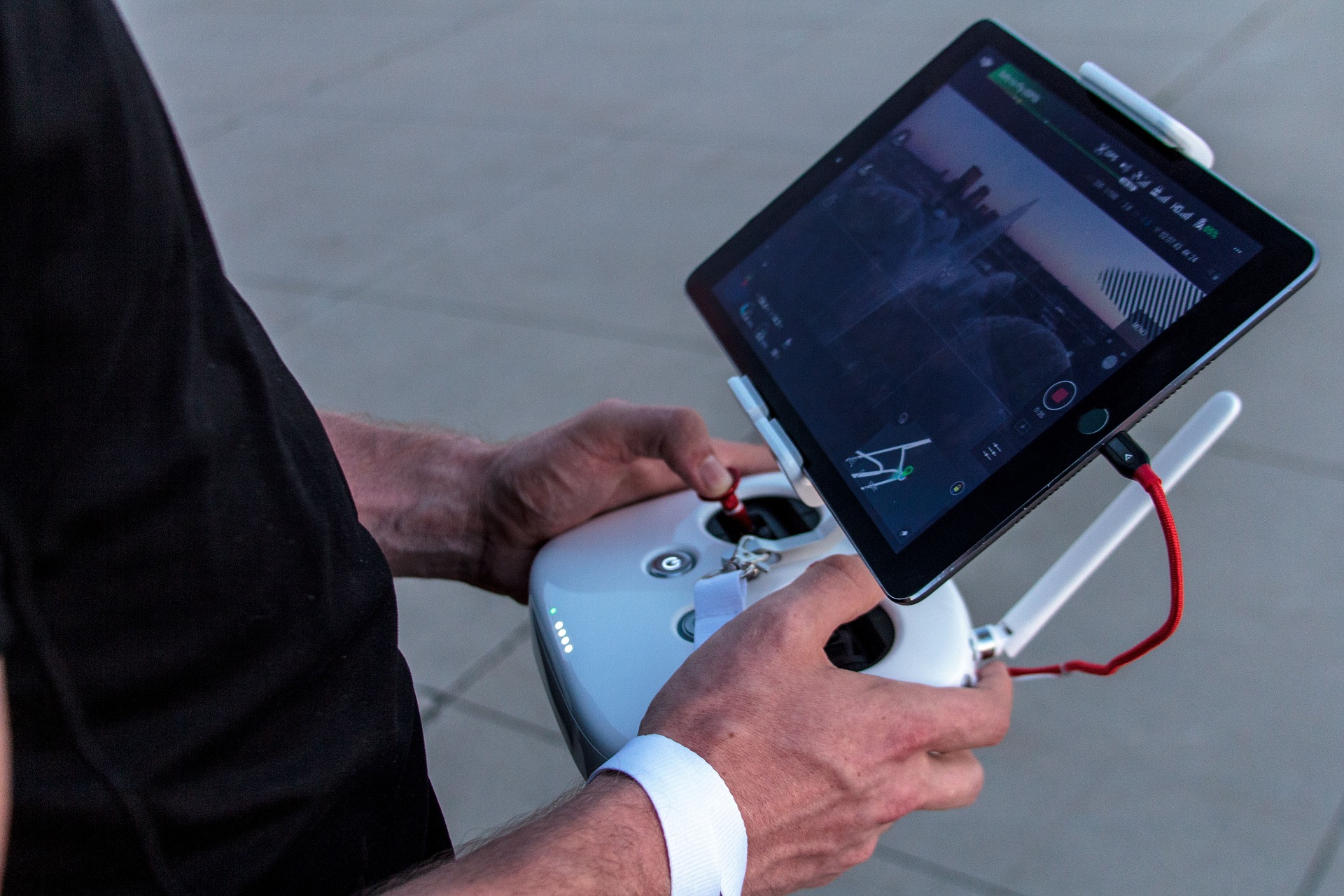 Mains d’un télépilote sur une radiocommande de drone équipée d’une tablette