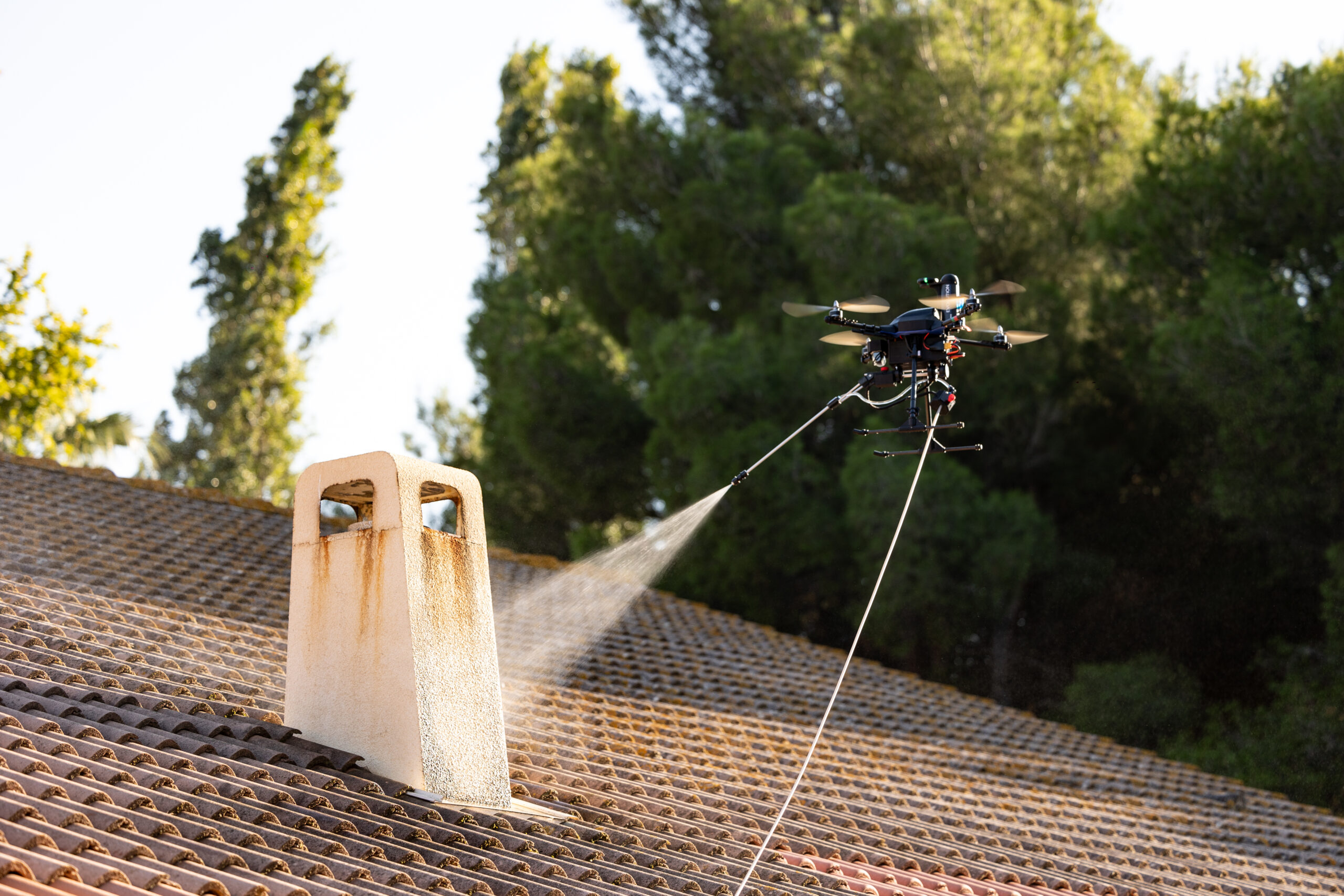 Drone pulvérisant un produit de nettoyage sur une toiture en tuiles